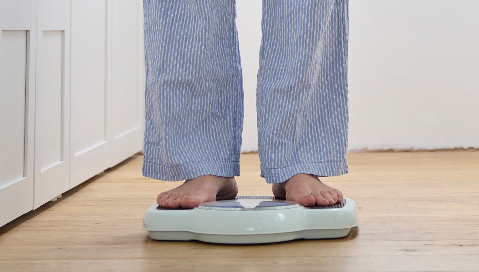 Kvinne med målebånd rundt magen og oppkneppede bukser